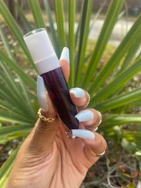 a hand holding a bottle of purple lip balm